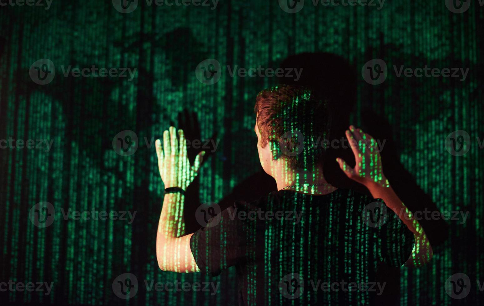 a dupla exposição de um homem caucasiano e fone de ouvido de realidade virtual vr é presumivelmente um jogador ou um hacker quebrando o código em uma rede ou servidor seguro, com linhas de código foto