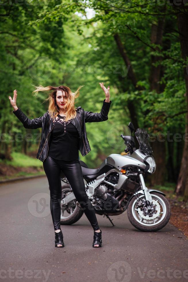 uma garota sexy atraente em uma moto esportiva posando do lado de fora foto