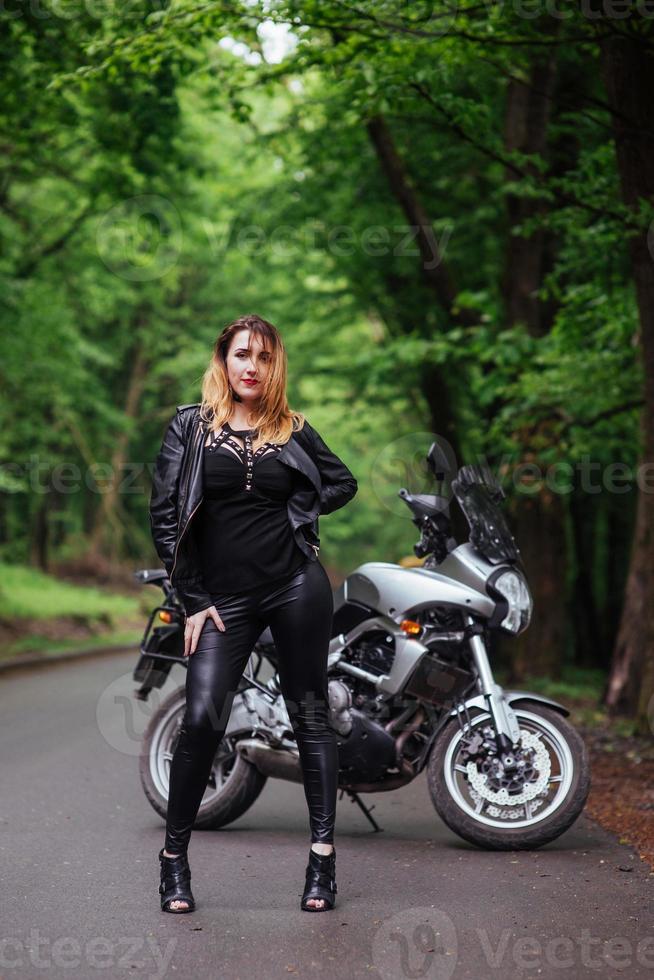 uma garota sexy atraente em uma moto esportiva posando do lado de fora foto