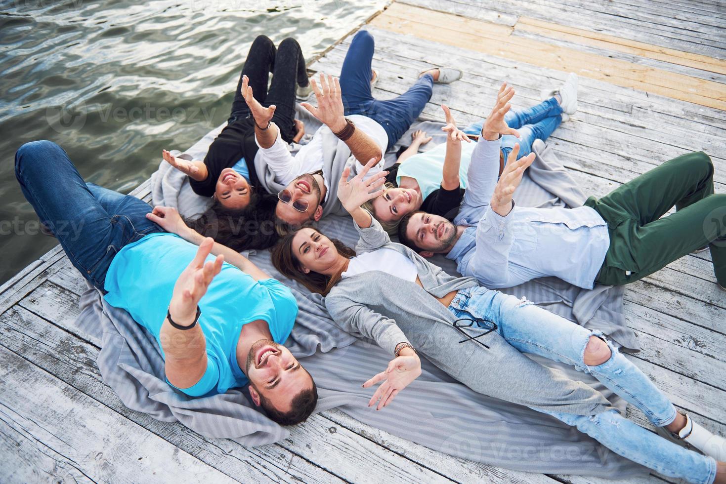 um grupo de jovens e bem sucedidos amigos de férias desfrutando de um jogo no lago. Emoções positivas. foto