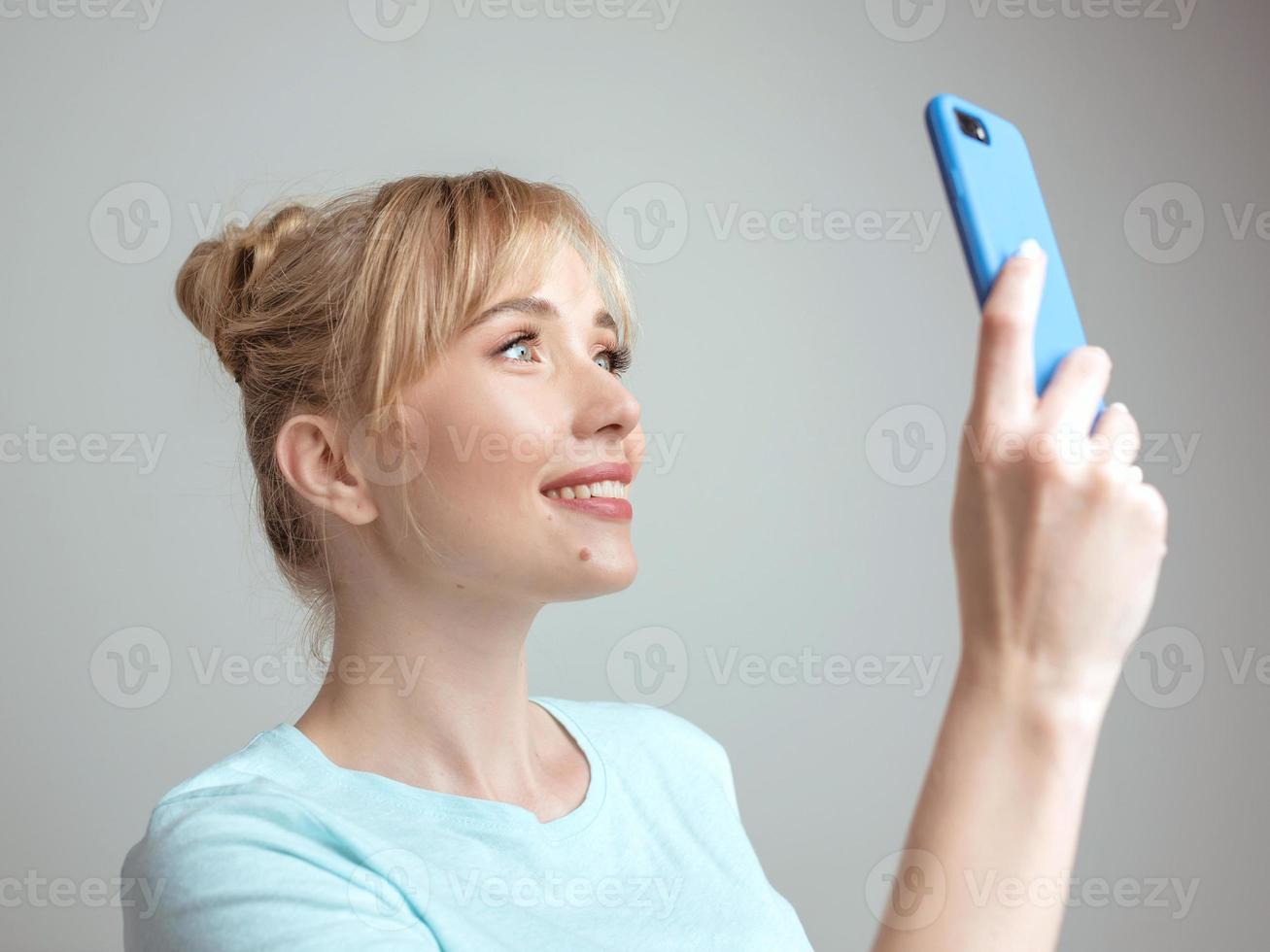 blogueira de mulher loira bonita elegante fazendo selfie com seu smartphone pela janela. tendência, tecnologia, beleza, conceito de moda foto