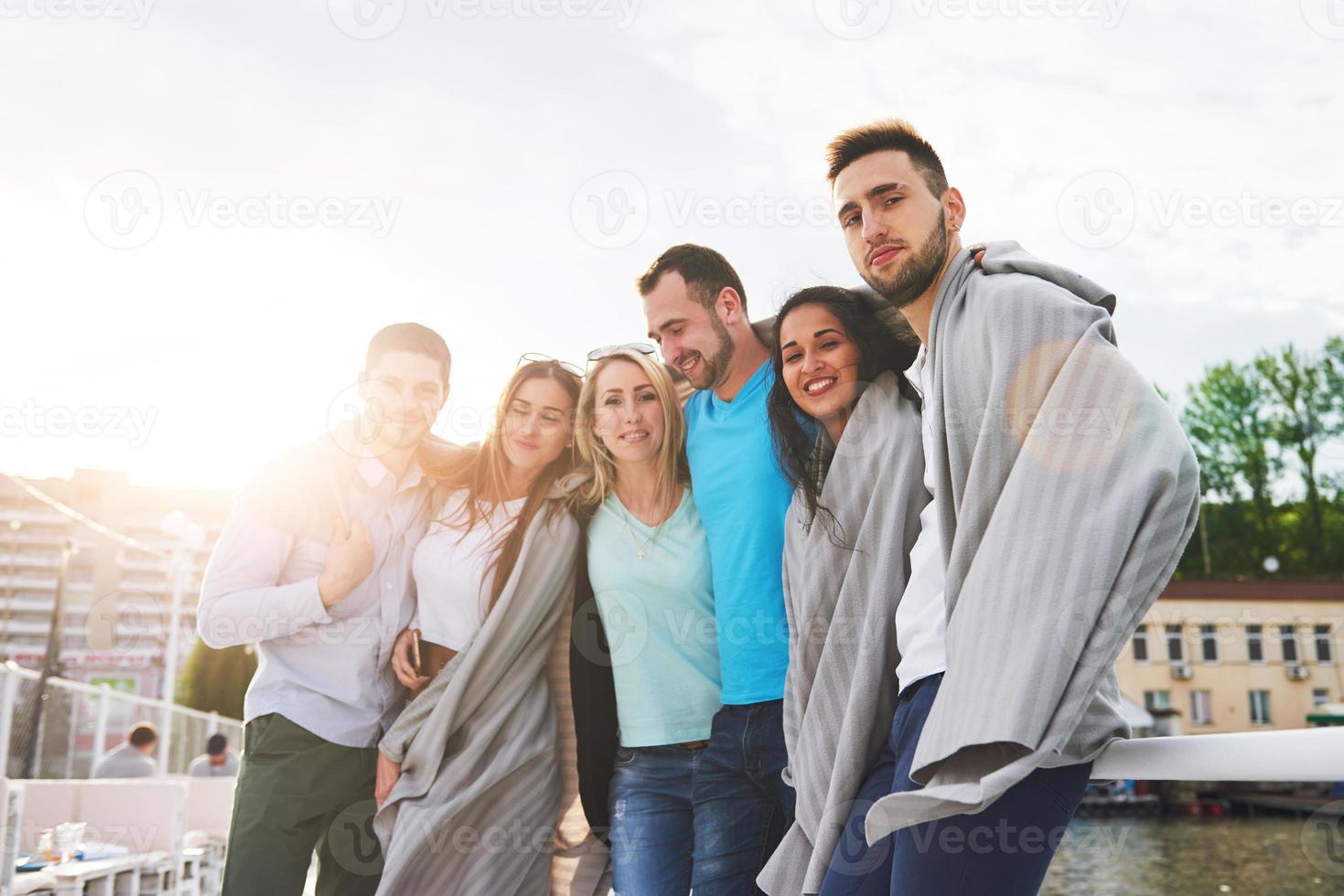 retrato de um grupo de jovens sentados à beira do cais, ao ar livre na natureza. amigos desfrutando de um jogo no lago. foto