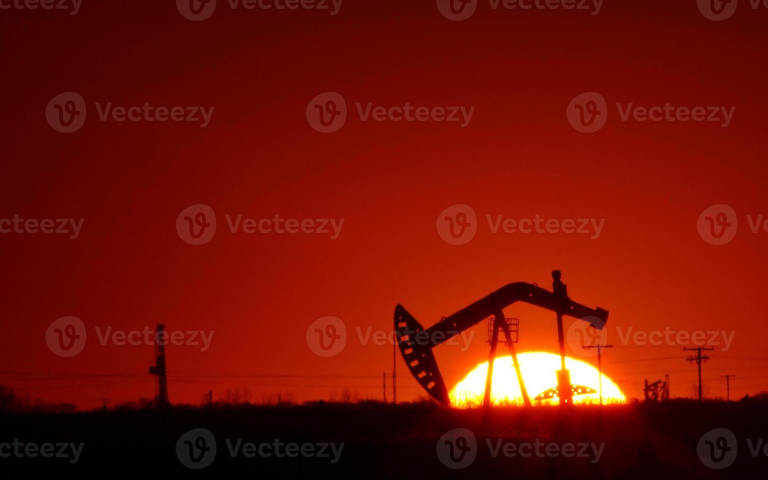 bomba de óleo no campo de saskatchewan ao pôr do sol foto