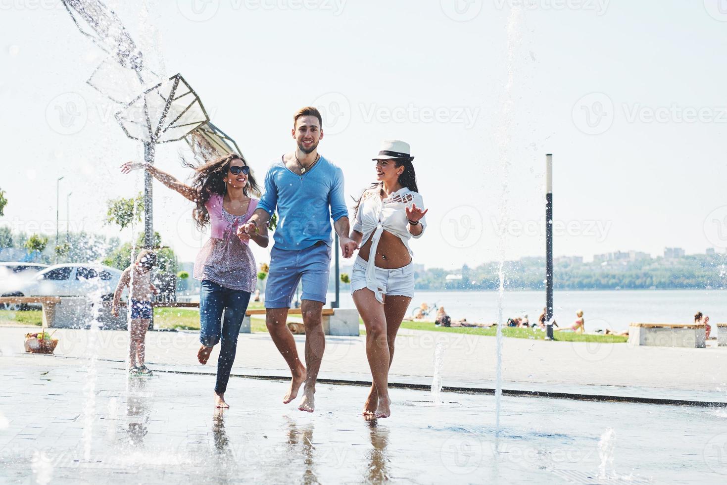 grupo de amigos se divertindo ao lado da fonte pública no dia de verão foto