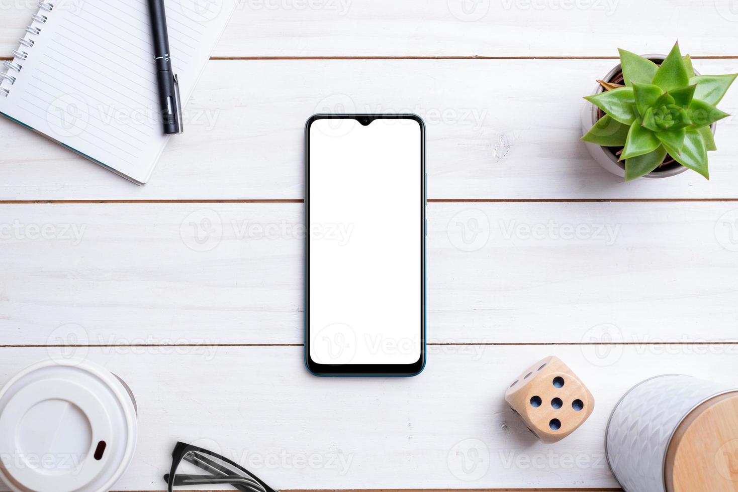 maquete de telefone na mesa de trabalho de madeira branca. composição da vista superior. exibição isolada para apresentação de design de aplicativo foto