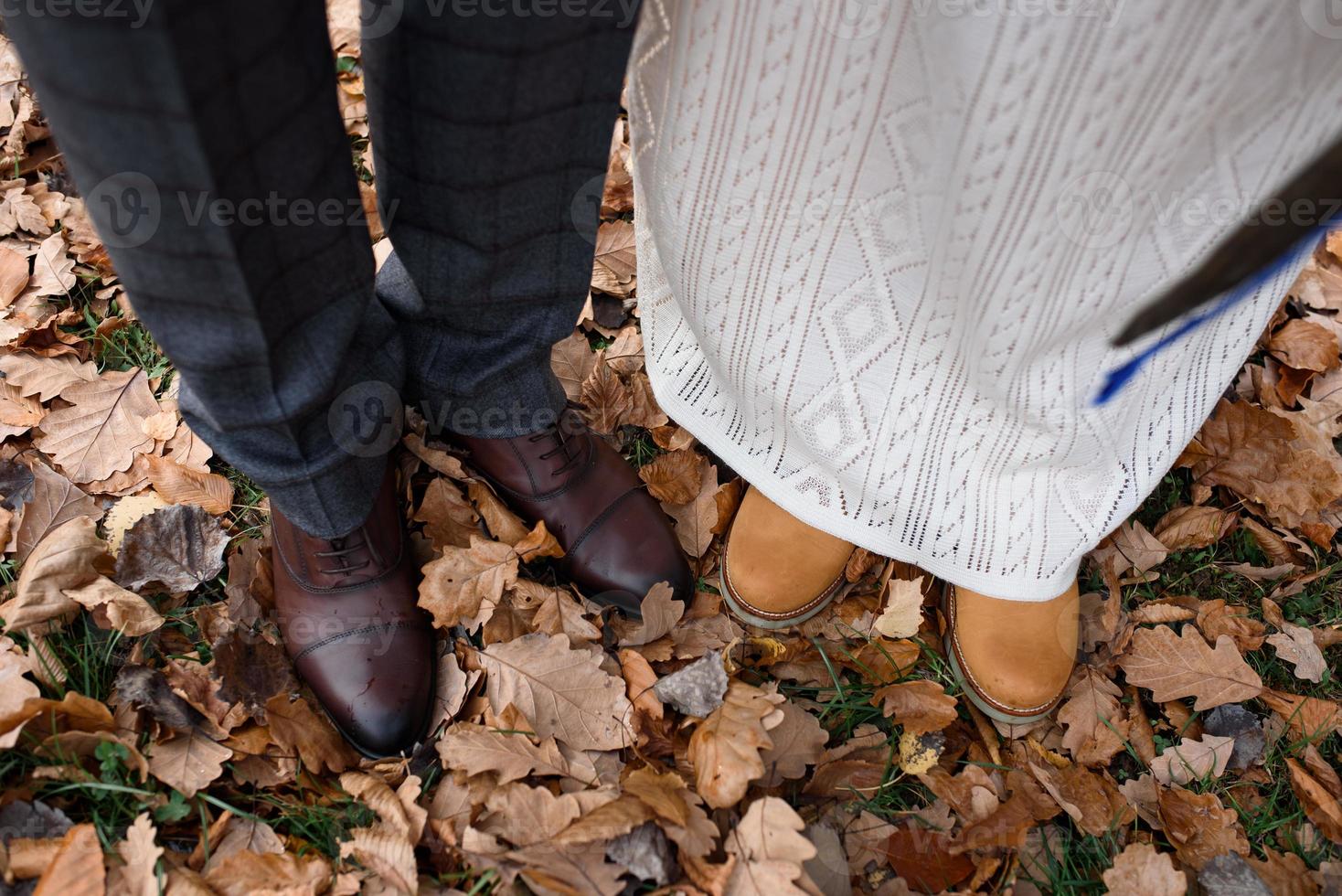 pés da noiva e do noivo, bem como seu filho no fundo das folhas de outono foto