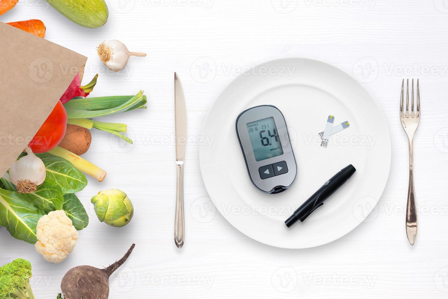 medidor de açúcar no sangue com tiras em um conceito de placa. saco com comida saudável e legumes ao lado. conceito de alimentação saudável e controle de diabetes foto