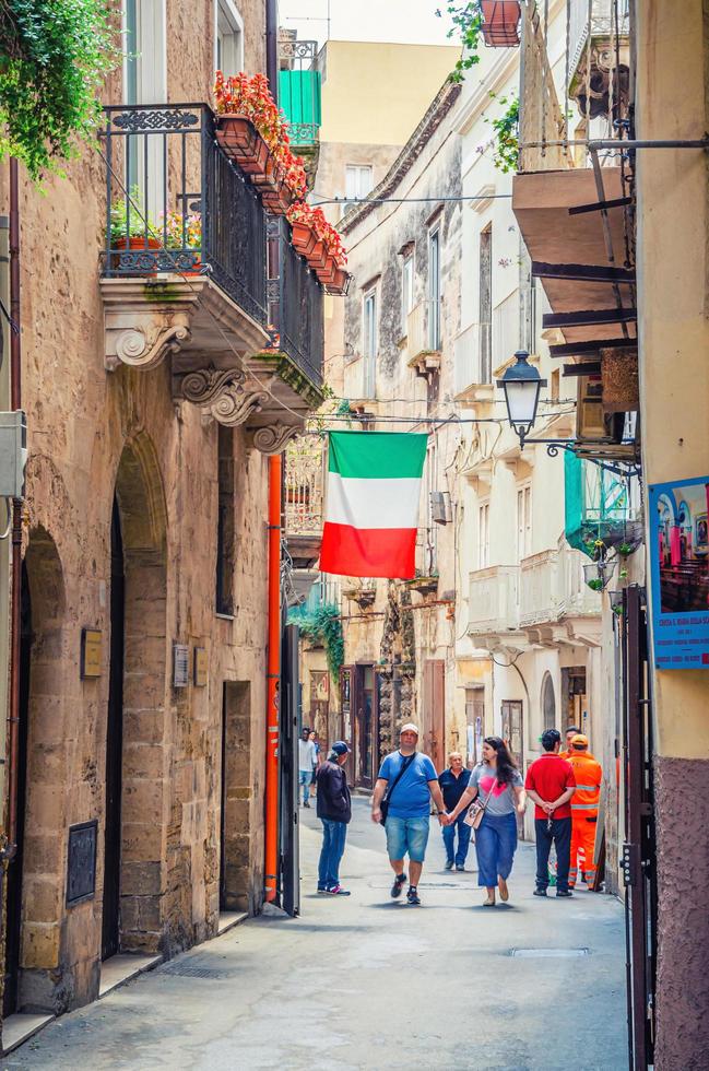 rua de paralelepípedos estreita italiana típica no centro histórico da cidade de taranto com homem e mulher andando foto
