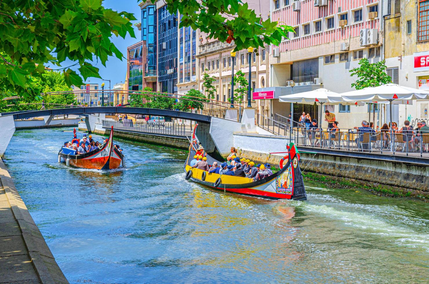 paisagem urbana de aveiro com o tradicional barco moliceiro colorido com turistas navegando no canal de águas estreitas foto