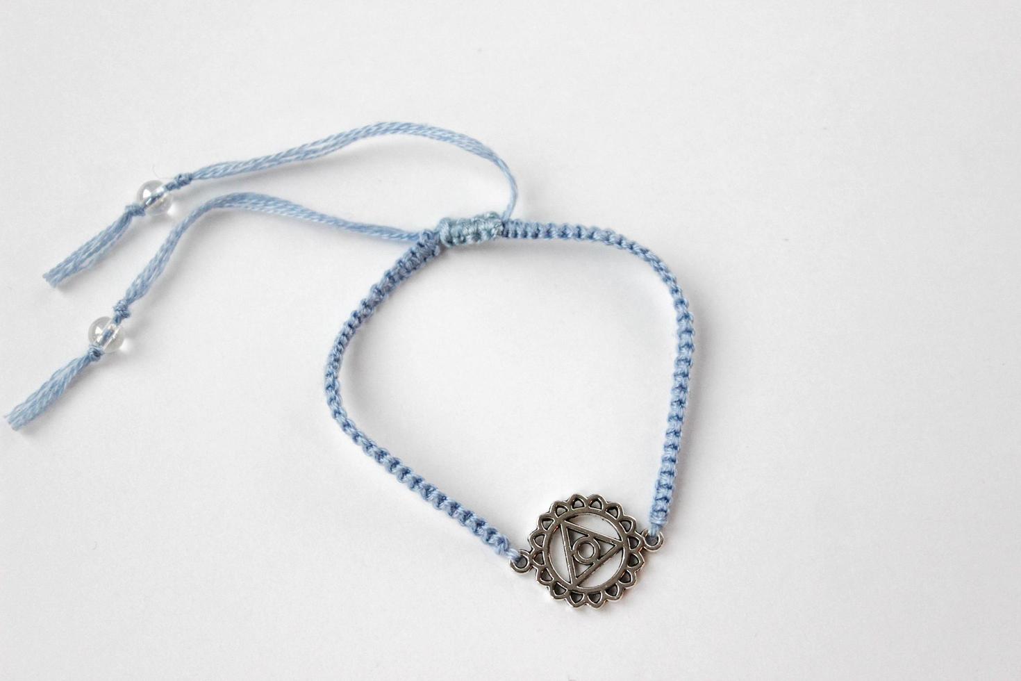 pulseira trançada azul com chakra vishuddha no fundo branco foto