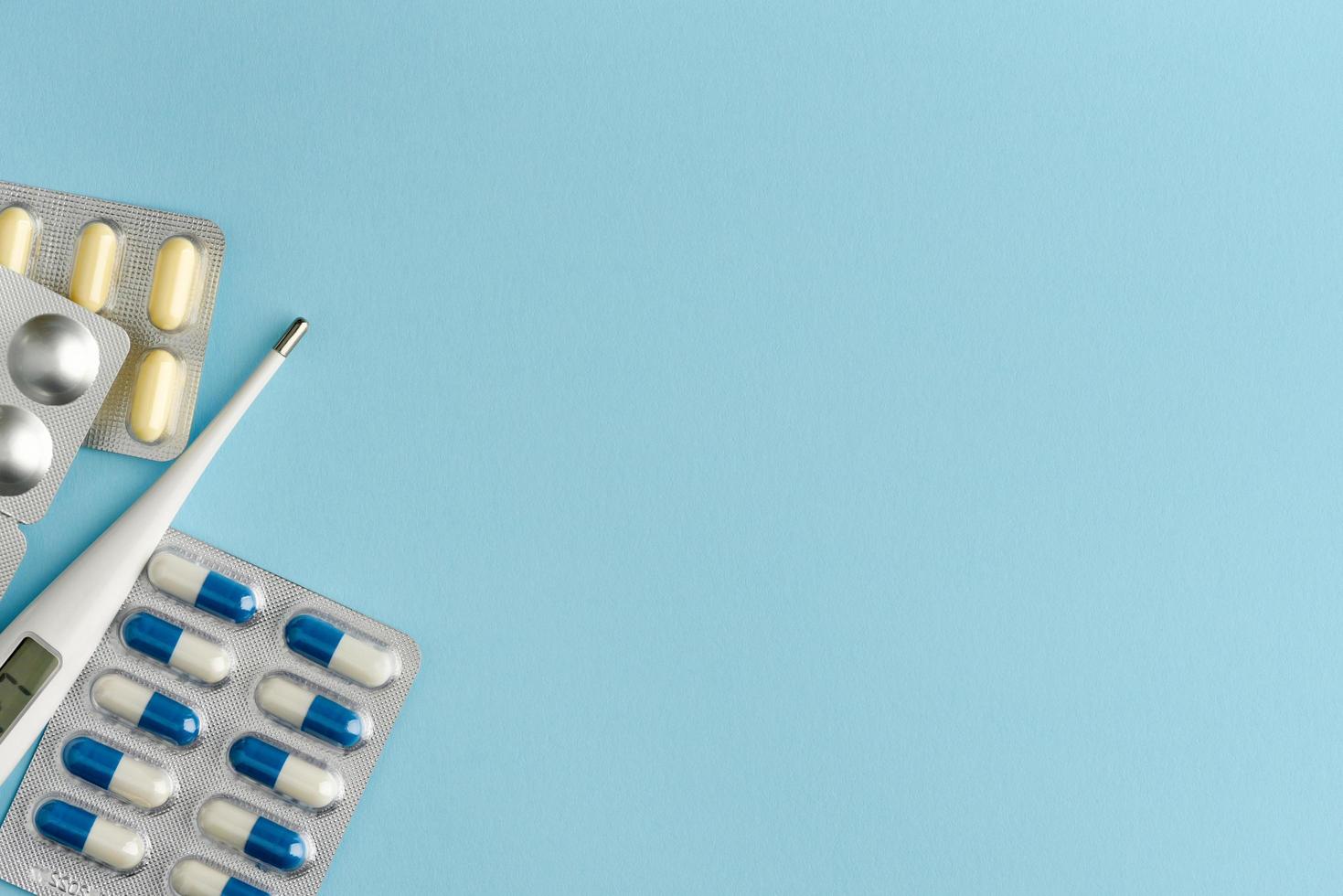 local de trabalho de medicina com pílulas e termômetro sobre fundo azul. foto