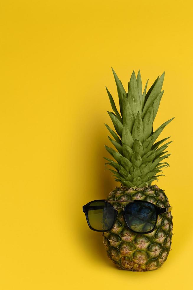 abacaxi engraçado em óculos de sol legais em um fundo amarelo foto