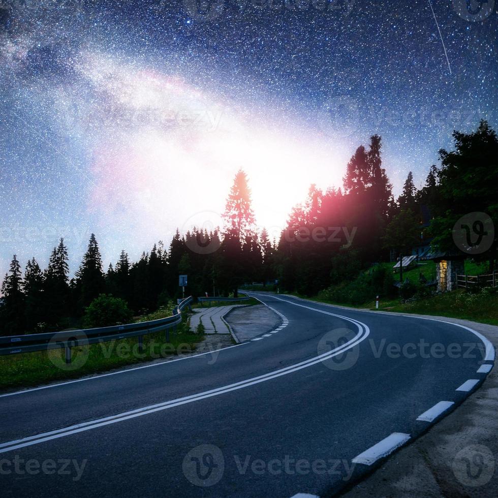 estrada de asfalto sob um céu noturno estrelado e a via láctea foto