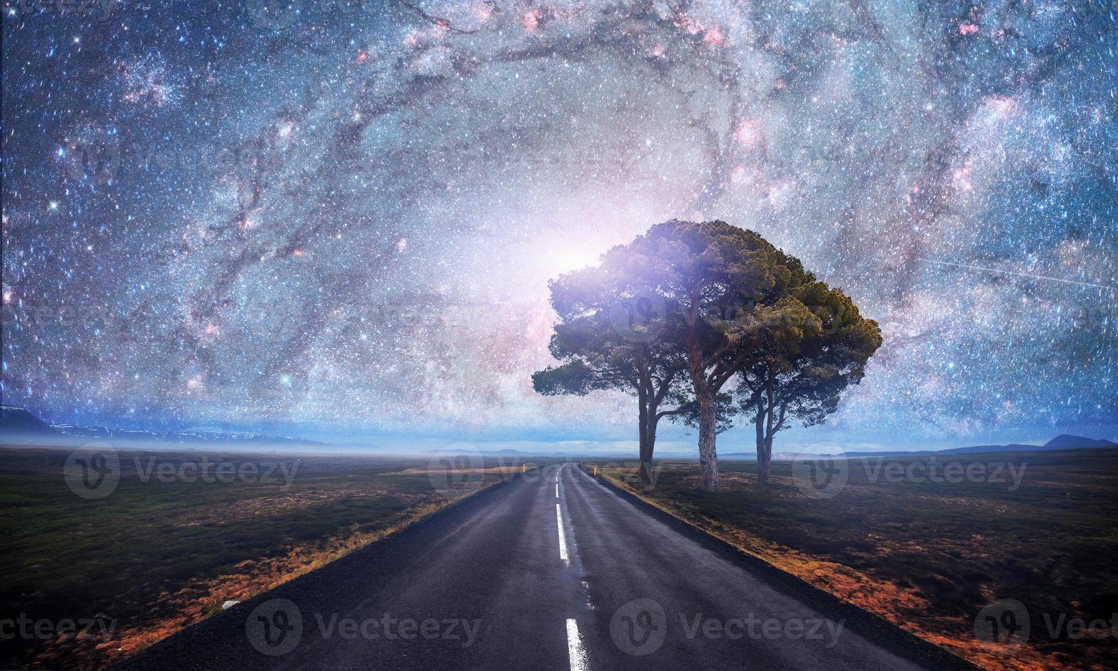 estrada de asfalto e árvore solitária sob um céu noturno estrelado e a via láctea. cortesia da nasa foto