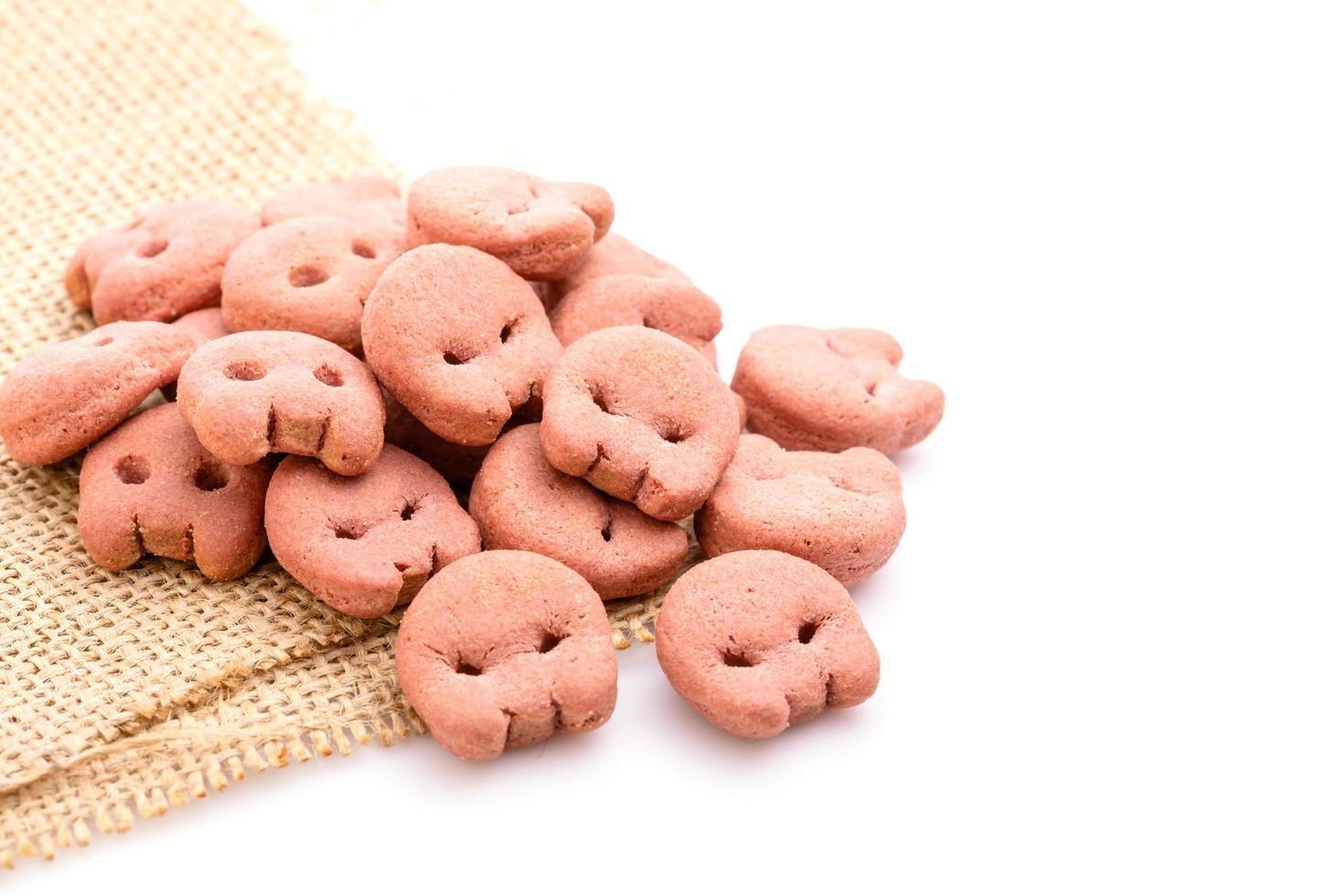 pilha de comida de cachorro biscoito rosa sabor de carne grelhada isolado no branco foto