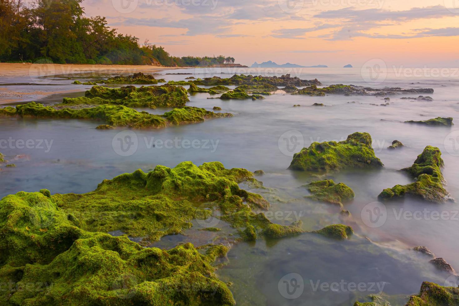 paisagem por do sol nas rochas da praia em primeiro plano foto