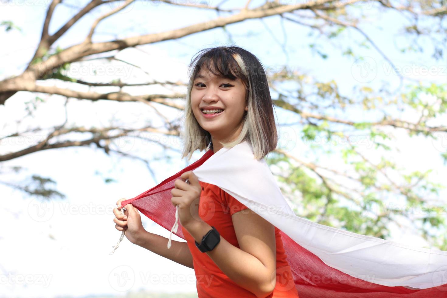 mulher asiática animada segurando a bandeira da Indonésia no dia da independência da Indonésia foto