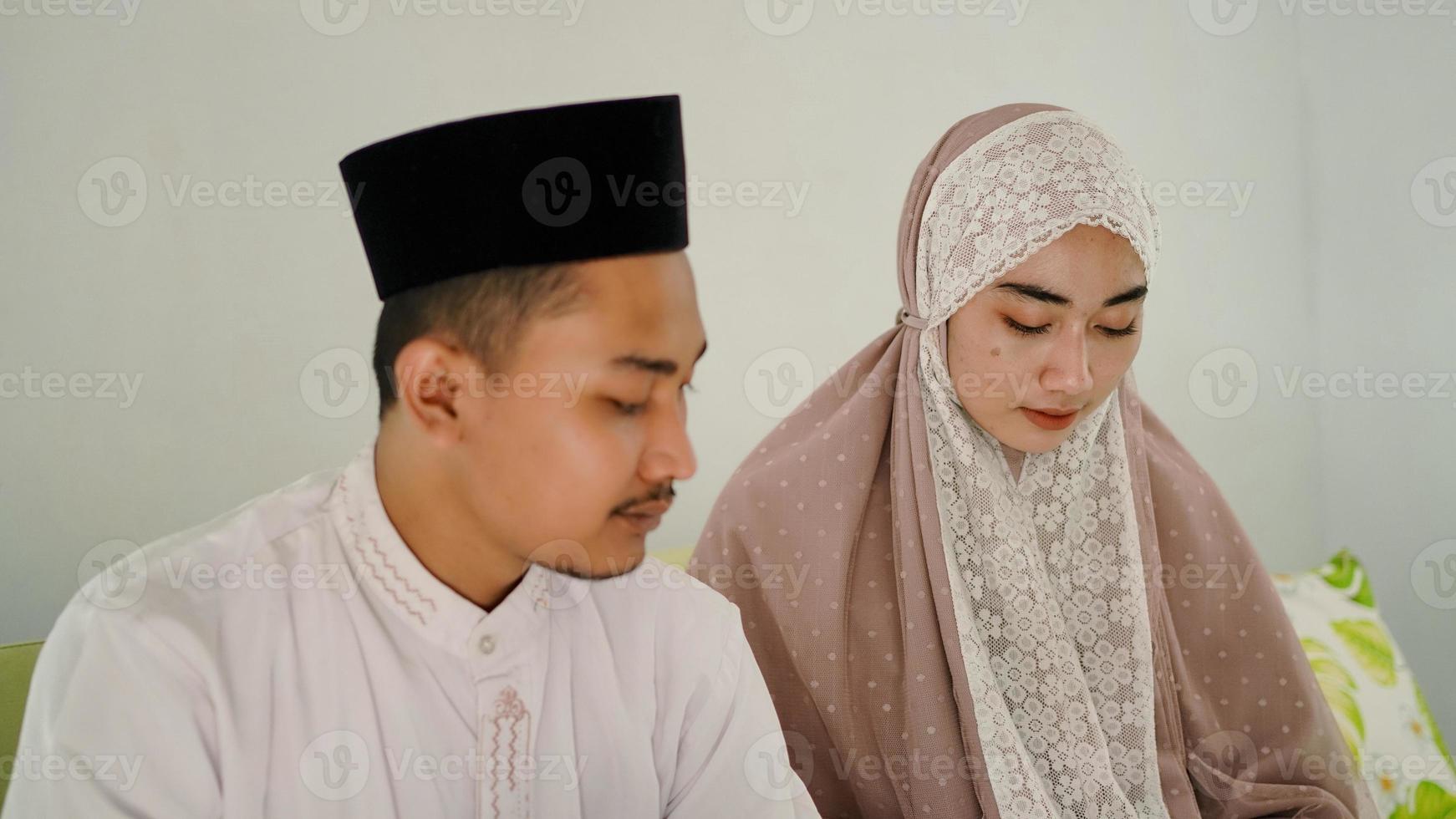 casal muçulmano asiático orando juntos em casa foto
