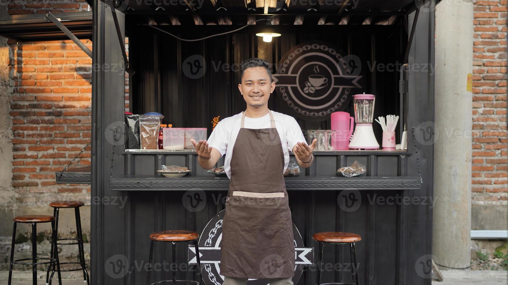 barista homem asiático atrai a atenção do cliente em café temático de contêiner foto