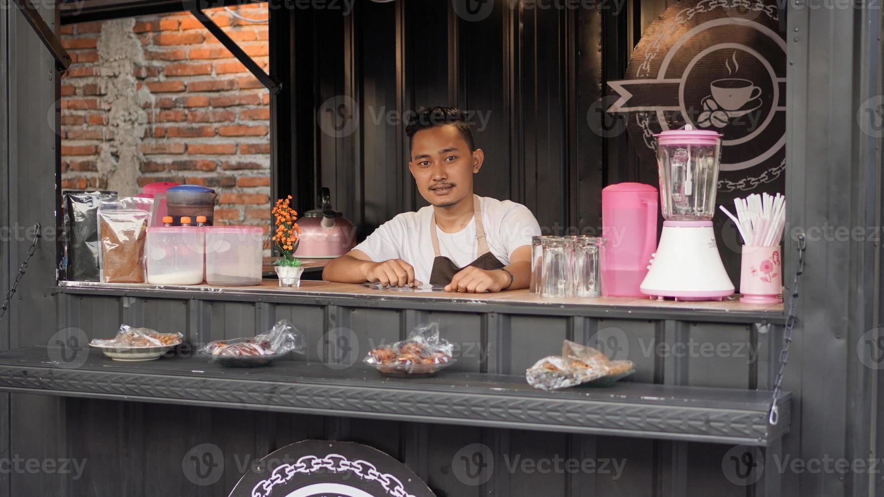 homem asiático em avental guardando contêiner angkringan foto