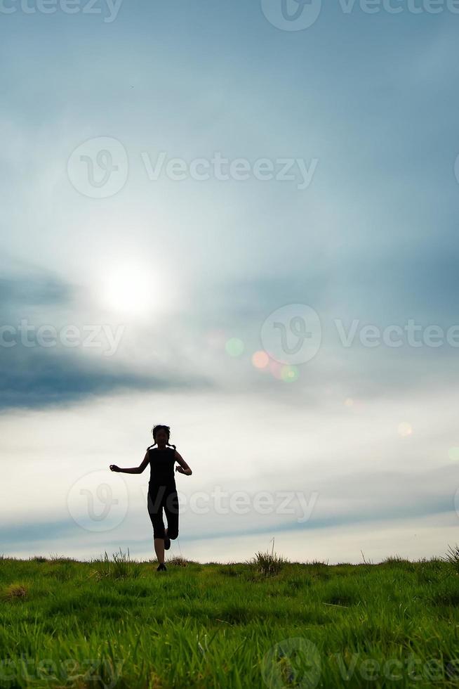 silhueta de uma garota com tranças correndo em um prado foto