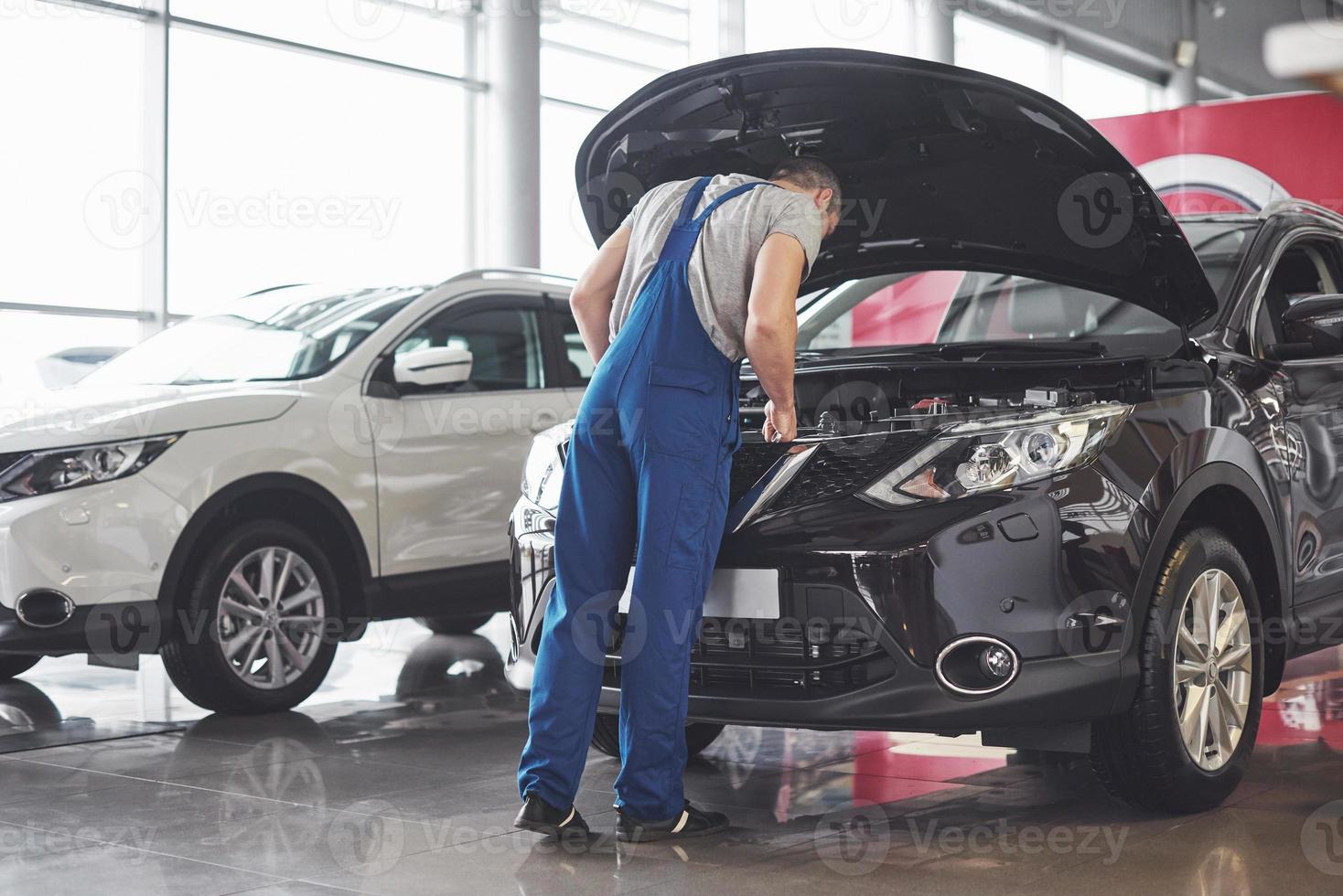 imagem mostrando trabalhador de serviço de carro musculoso consertando veículo foto