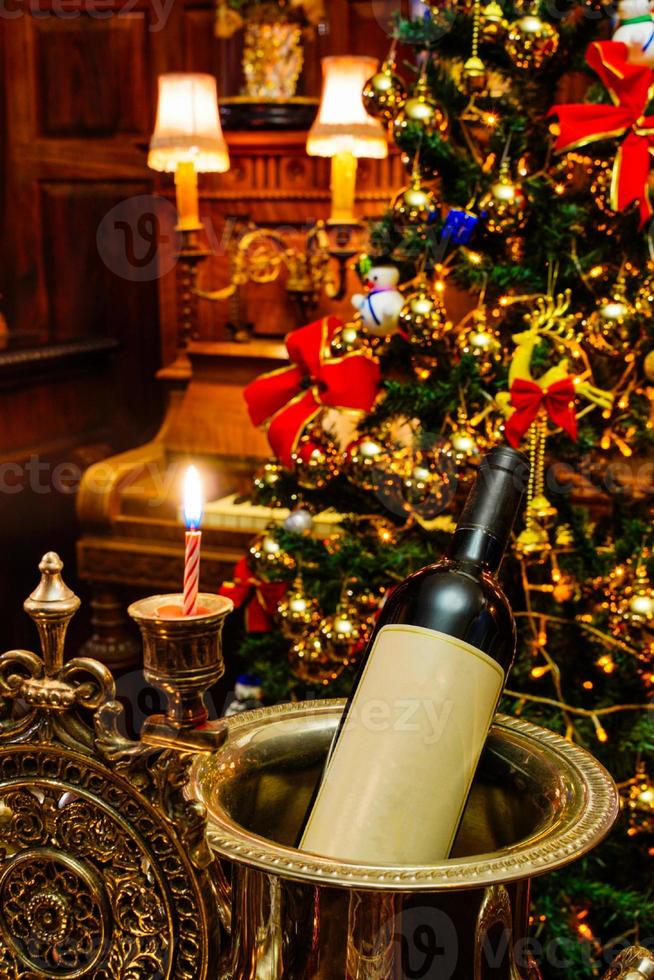 garrafa de vinho na celebração do feriado de natal. decoração da sala em dezembro festivo, inverno sazonal. fundo bonito. interior do quarto de ornamento de luz dourada. foto