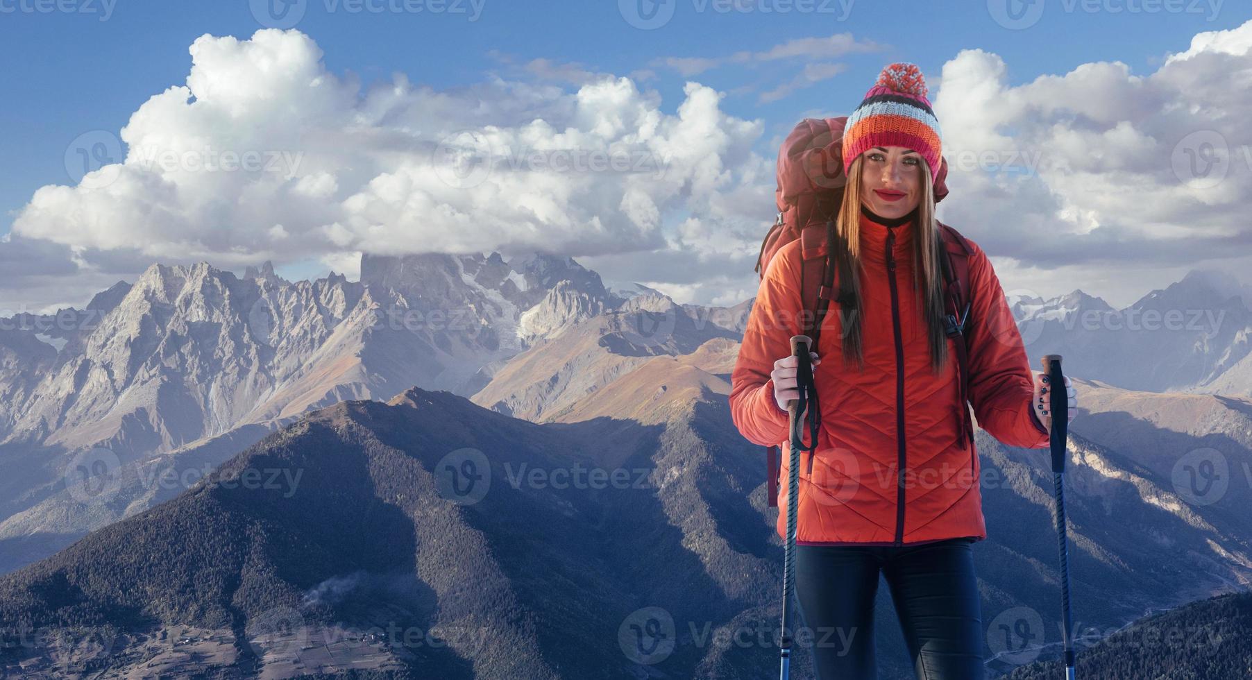 uma mulher com uma mochila descansa no topo da montanha e aprecia a vista do vale foto