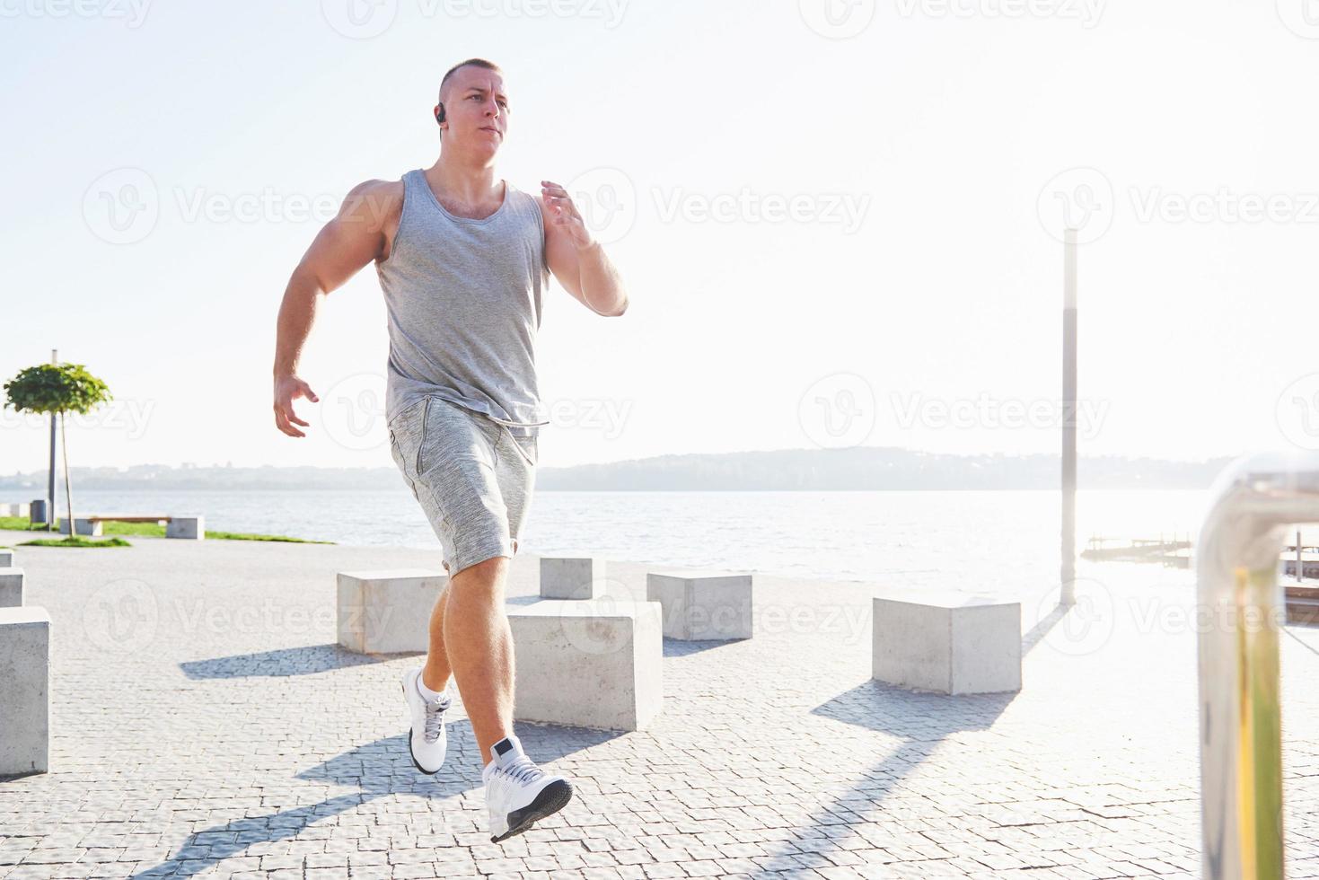 corredor de homem fazendo exercícios de alongamento, preparando-se para o treino matinal no parque foto