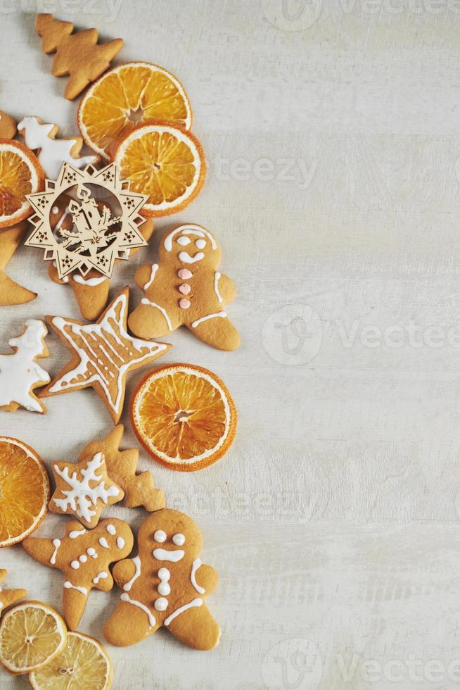 biscoitos de gengibre de natal e laranja seca e especiarias na mesa branca foto