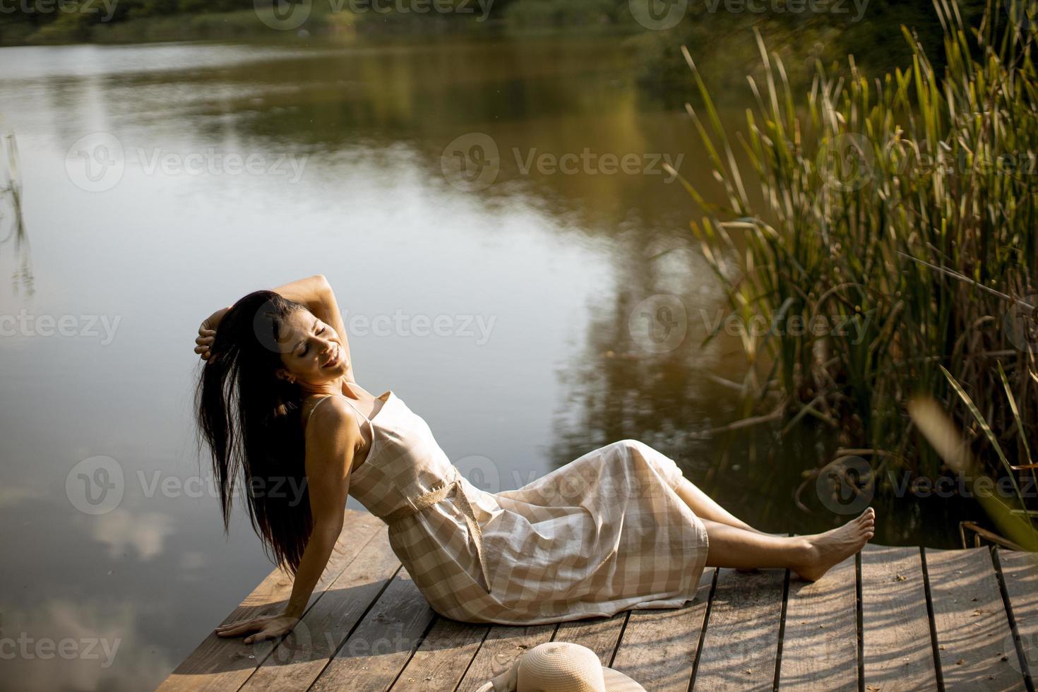 jovem relaxante no cais de madeira no lago calmo foto