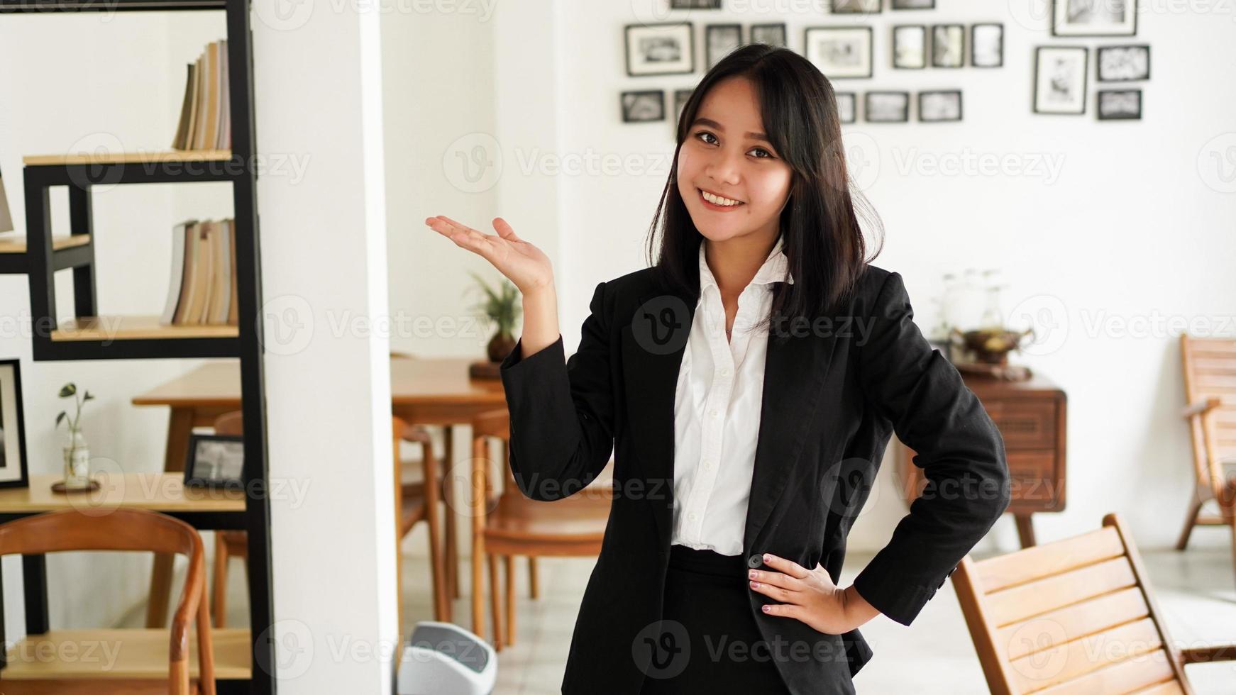 bela jovem mulher de negócios asiáticos de terno e apontando as mãos do dedo para cima no escritório foto