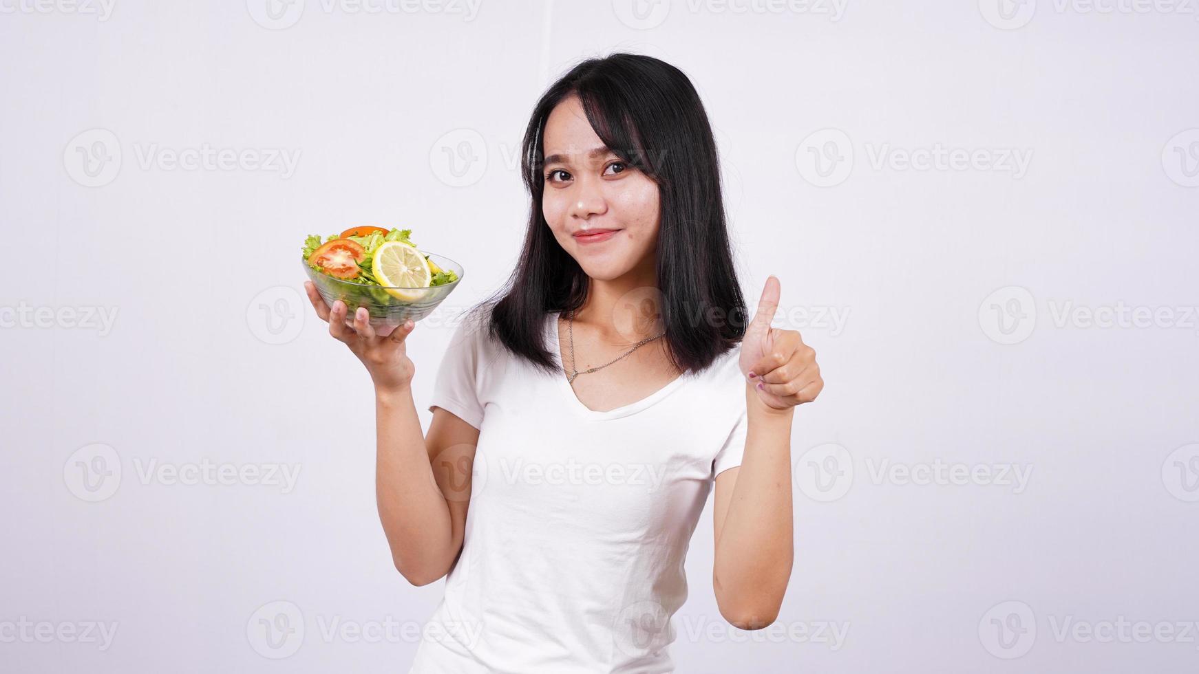 mulheres asiáticas e dedo bem em uma tigela de salada de legumes frescos com fundo branco isolado foto