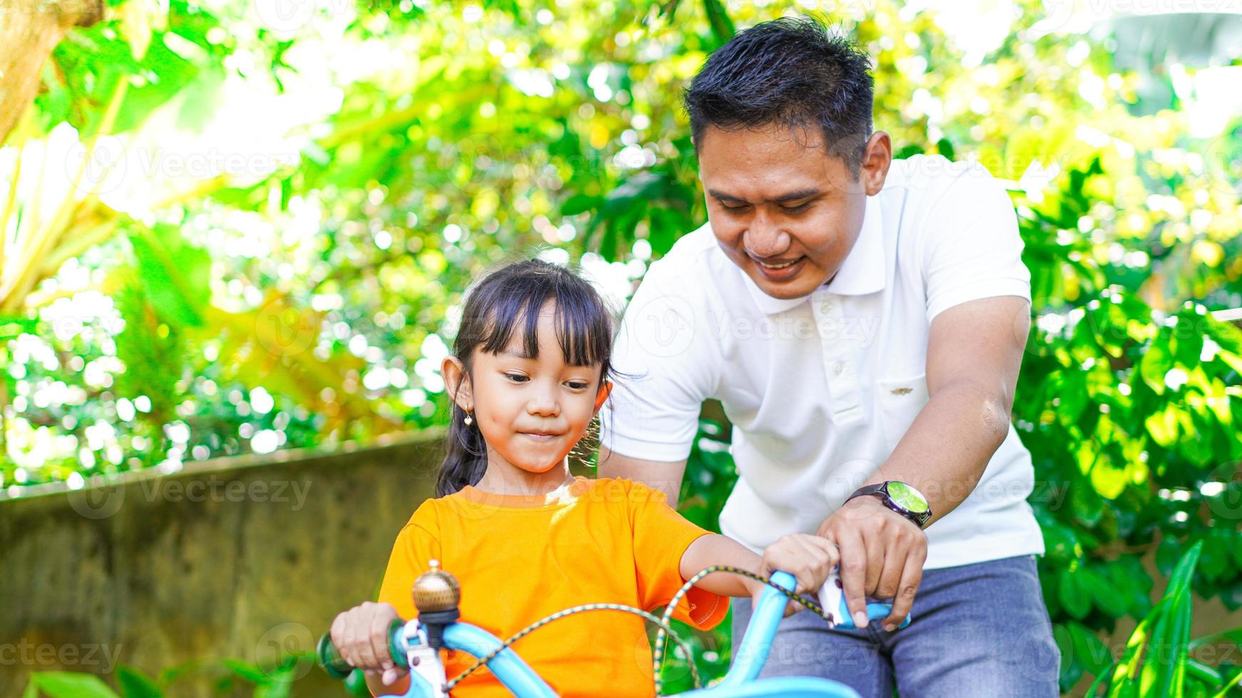 pai e filha brincando de bicicleta no parque foto