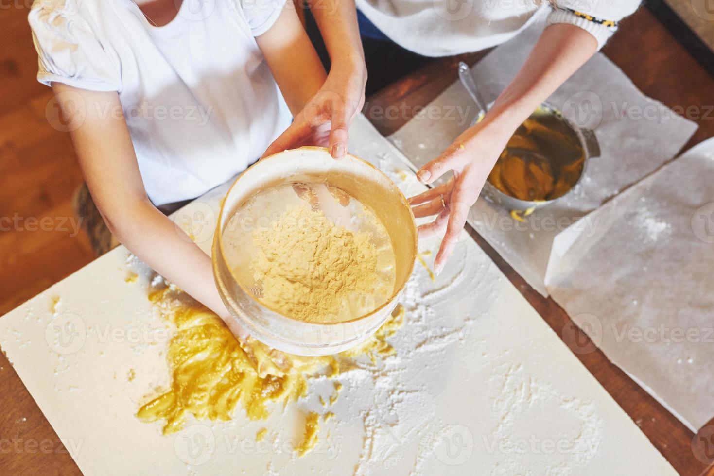 uma garota feliz usa uma massa. bebê faz o jantar em terno de chef foto