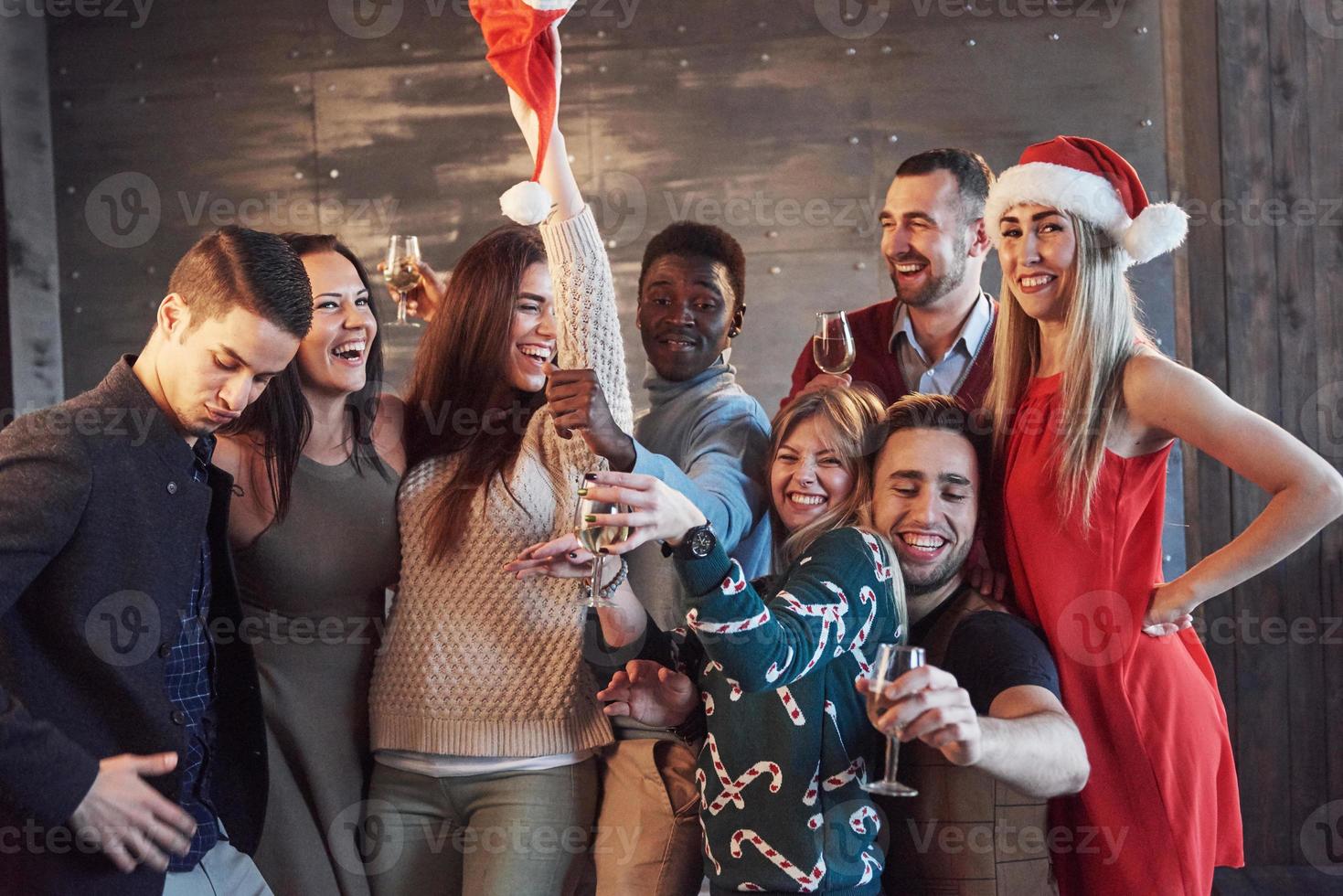 festa com amigos. eles amam o natal. grupo de jovens alegres carregando estrelinhas e taças de champanhe, dançando na festa de ano novo e parecendo feliz. conceitos sobre estilo de vida de união foto