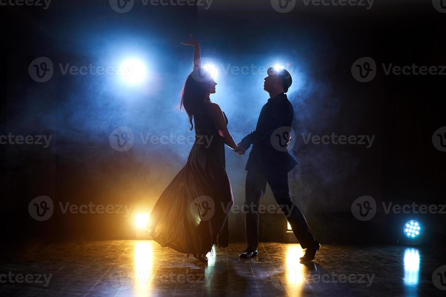 dançarinos habilidosos se apresentando no quarto escuro sob a luz e a fumaça do show. casal sensual realizando uma dança contemporânea artística e emocional foto