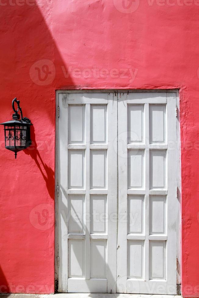 velha porta branca com lustre vintage pendurado na parede vermelha foto