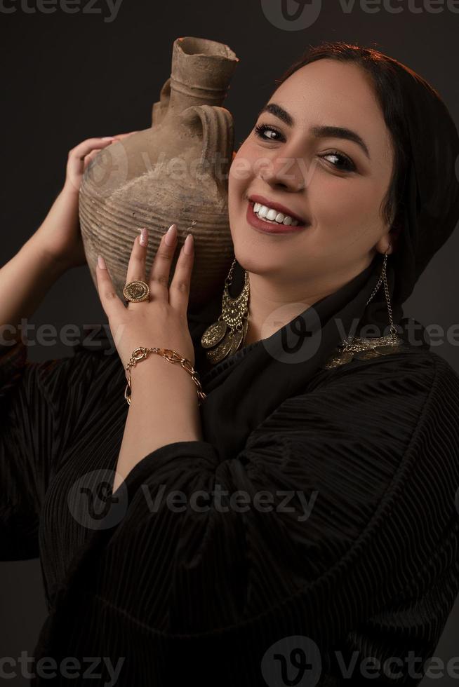 mulher de preto segurando vaso na cabeça foto