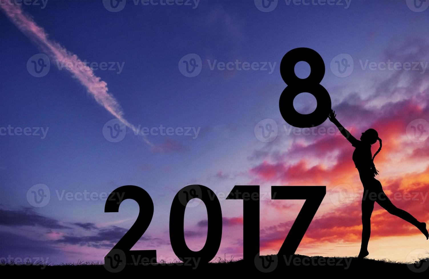 silhueta da garota que detém os números do ano novo por do sol. conceito de substituição 2017 a 2018 foto