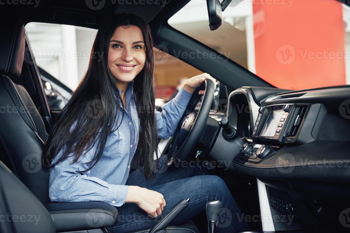 negócio de automóveis, venda de carros, consumismo e conceito de pessoas - mulher feliz pegando a chave do carro do revendedor no salão de automóveis ou salão foto