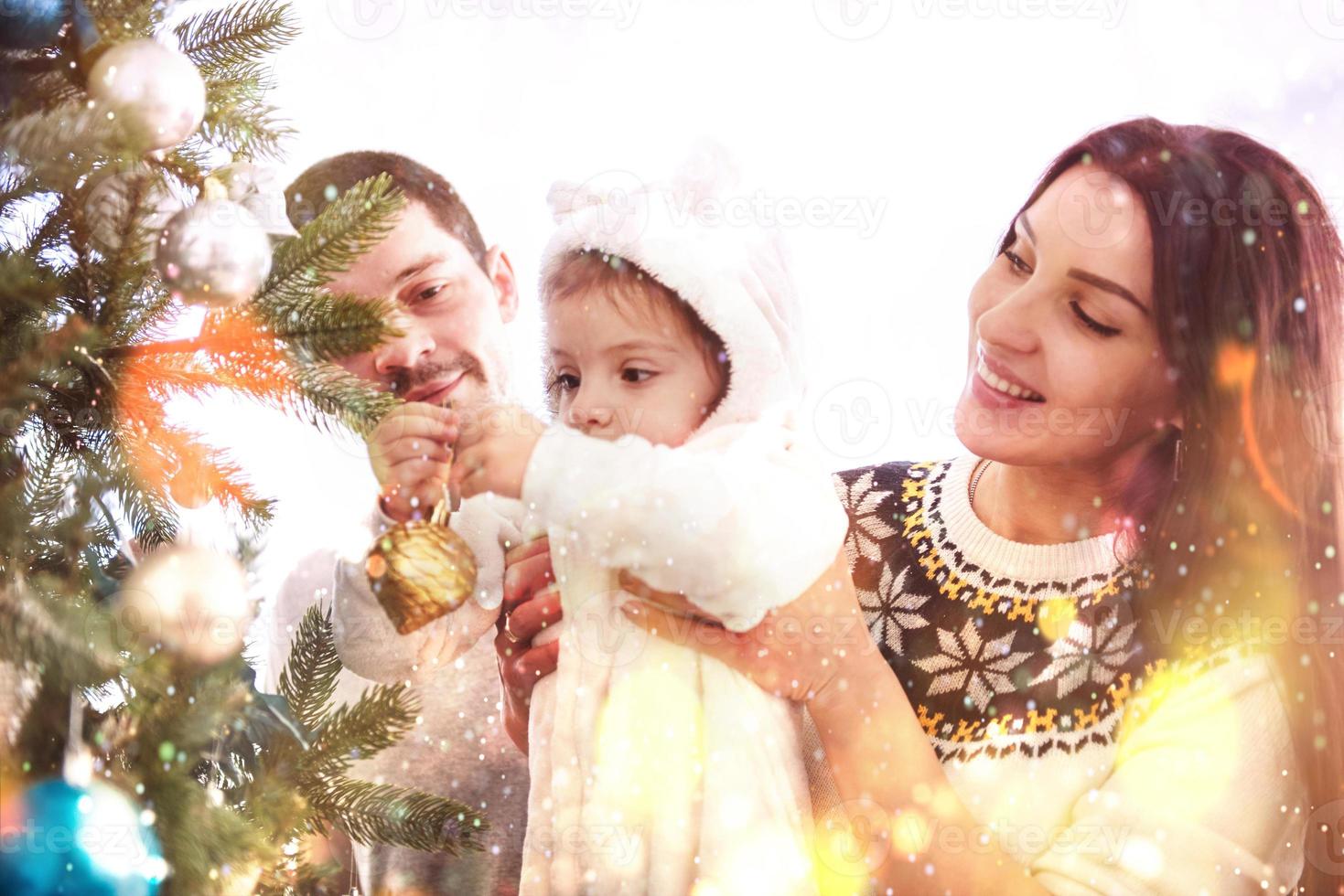 família feliz decorando a árvore de natal juntos. pai Mae e filha. criança fofa foto