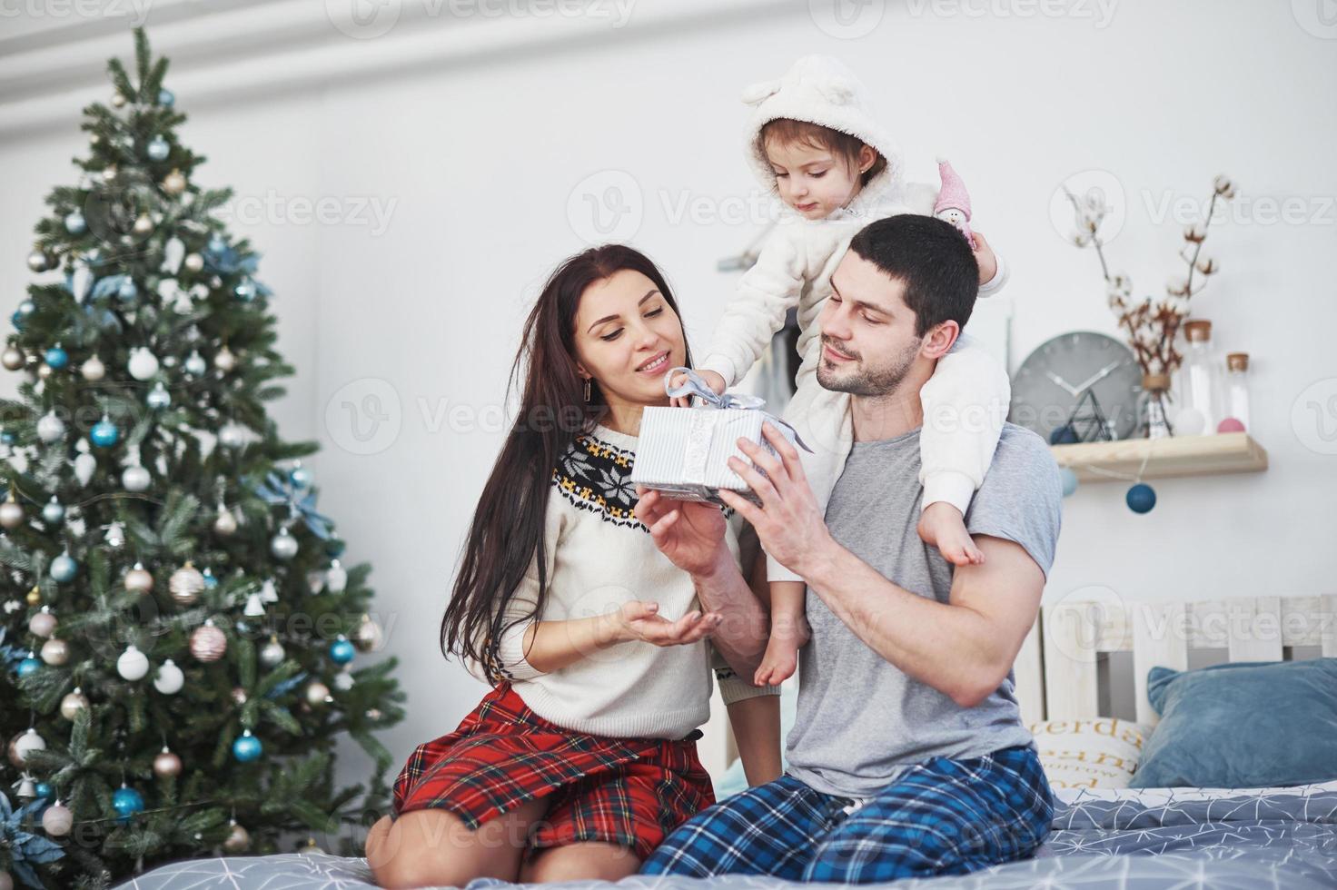 família feliz no Natal de manhã abrindo presentes juntos perto do abeto. o conceito de felicidade e bem-estar familiar foto