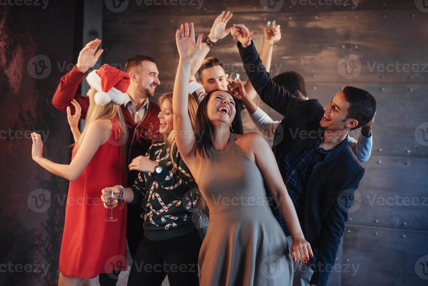 festa com amigos. eles amam o natal. grupo de jovens alegres carregando estrelinhas e taças de champanhe, dançando na festa de ano novo e parecendo feliz. conceitos sobre estilo de vida de união foto