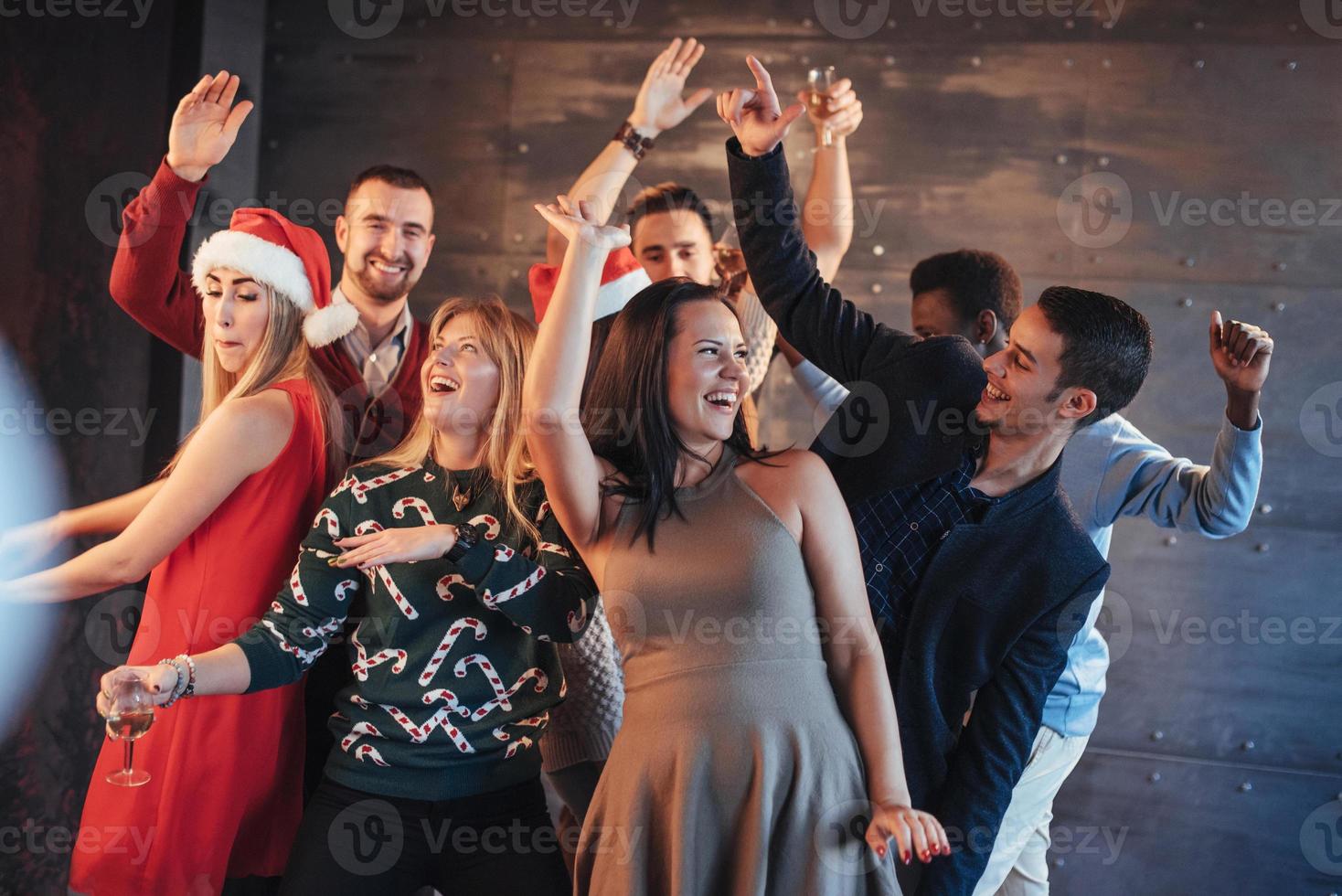 festa com amigos. eles amam o natal. grupo de jovens alegres carregando estrelinhas e taças de champanhe, dançando na festa de ano novo e parecendo feliz. conceitos sobre estilo de vida de união foto