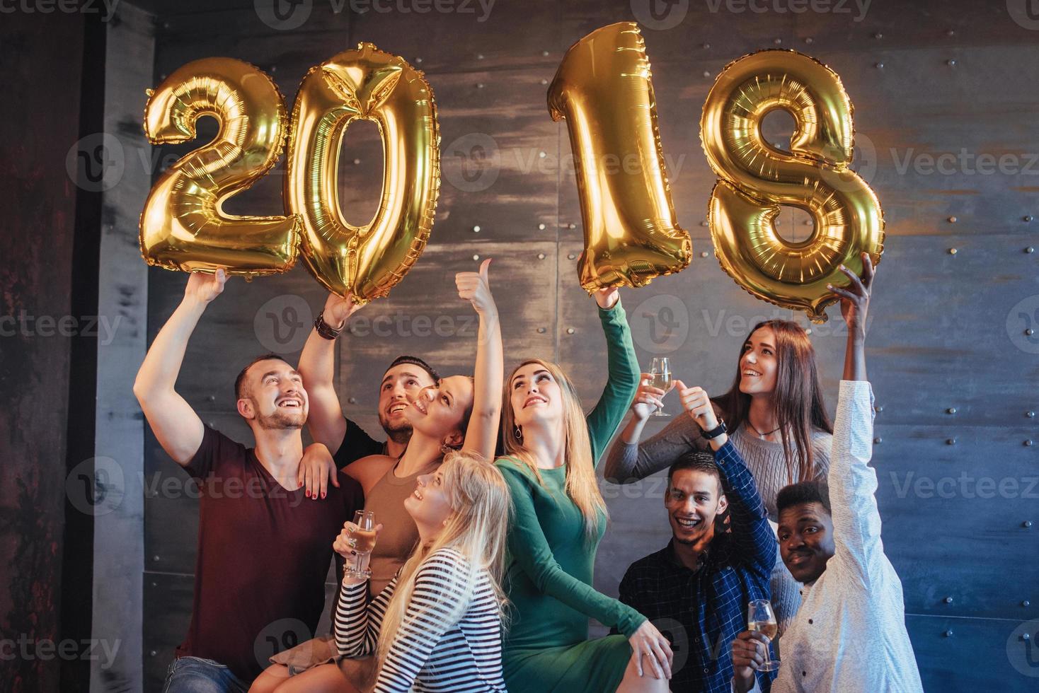 um grupo de jovens alegres segura números que indicam a chegada de um novo ano de 2018. a festa é dedicada à celebração do ano novo. conceitos sobre estilo de vida de união da juventude foto
