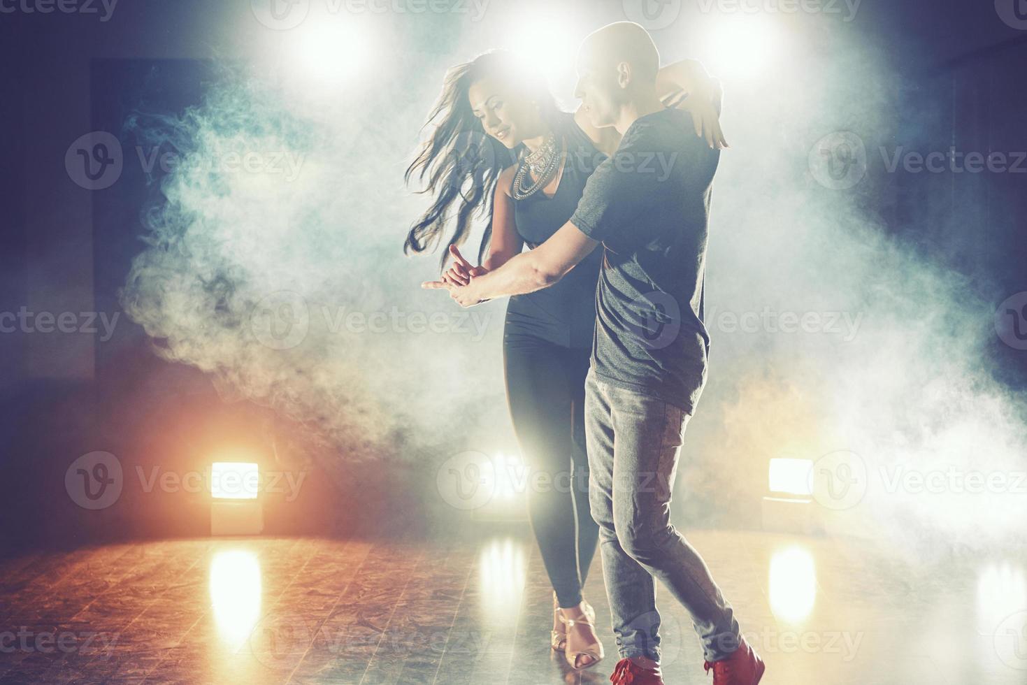 dançarinos habilidosos se apresentando no quarto escuro sob a luz e a fumaça do show. casal sensual realizando uma dança contemporânea artística e emocional foto