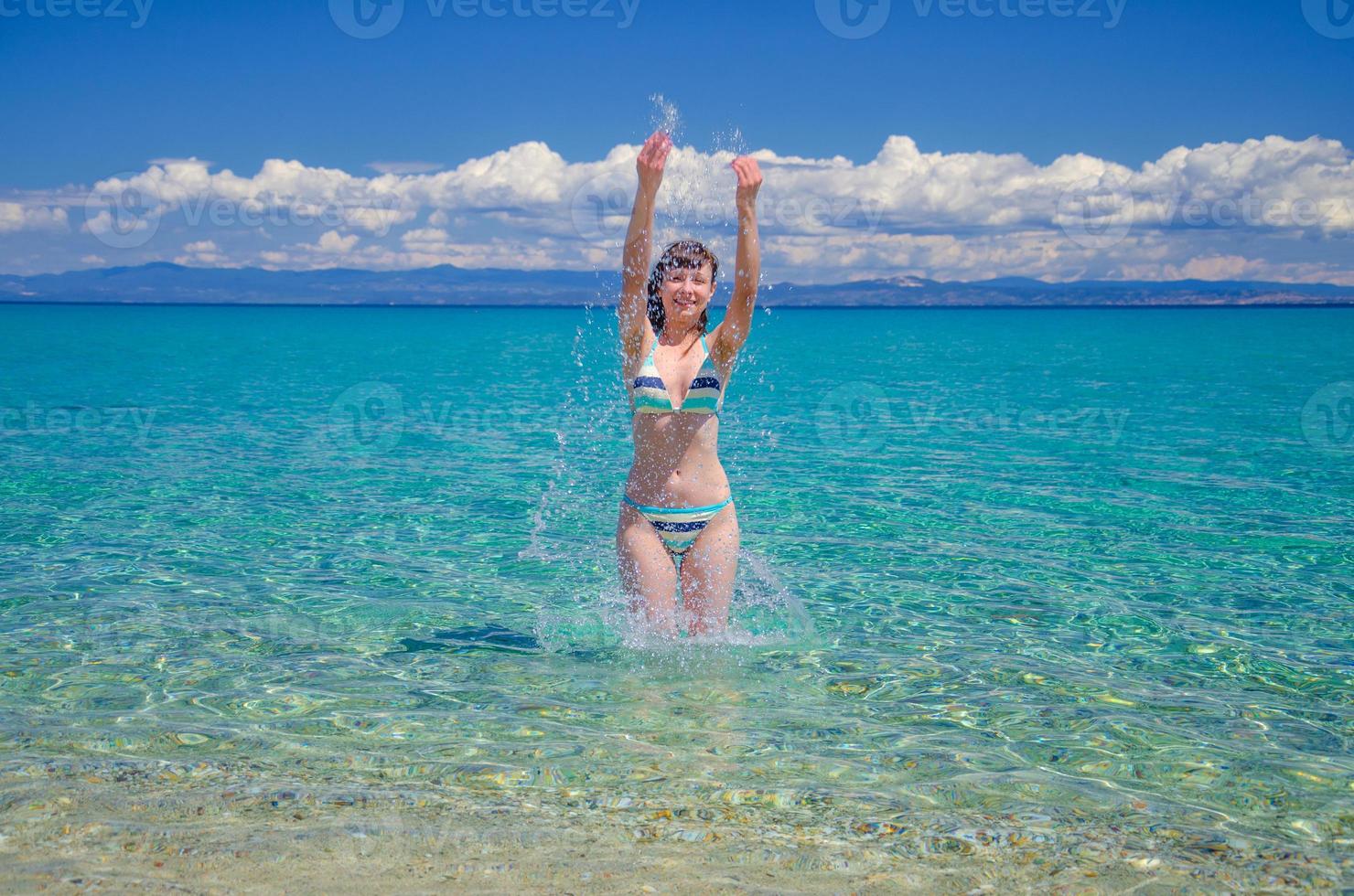 jovem linda de biquíni ficar na água turquesa do golfo de toroneos kolpos foto