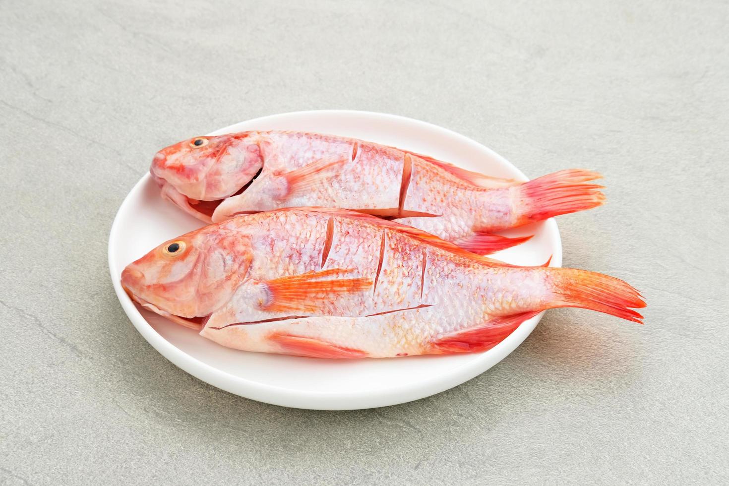 peixe tilápia vermelho cru é um tipo de consumo de peixe de água doce, servido na chapa branca com especiarias e limão. foco selecionado foto