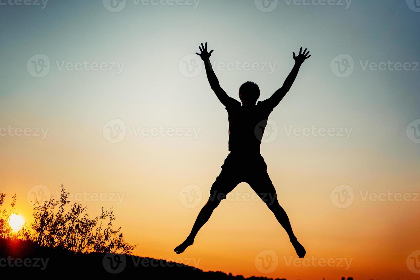 homem feliz pulando de alegria ao pôr do sol. conceito de sucesso e felicidade foto